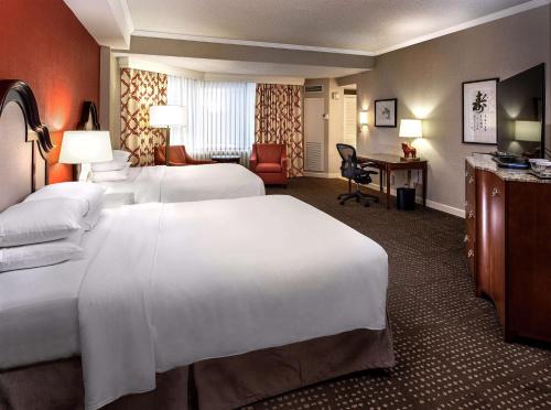a hotel room with two beds and a desk at Hilton Anatole in Dallas