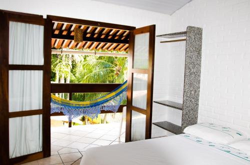 a bedroom with a bed and a window with a hammock at Hotel Tubarão in Natal
