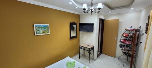 Cette chambre est dotée de murs jaunes et d'une télévision murale. dans l'établissement Apartamento completo no Centro histórico, à Ouro Preto