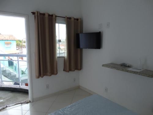 a room with a bed and a tv and a window at Nacif&Alcantara Suítes in Tamoios