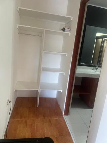 a closet with white shelves and a desk at Cómodo dormitorio in Quepos