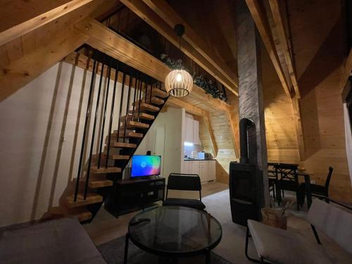 a living room with a staircase and a television at KoCHALET Apartment in Crni Vrh