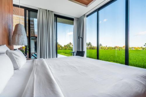 a bedroom with a large white bed and large windows at GREEN FLOW Villas Ubud I in Ubud