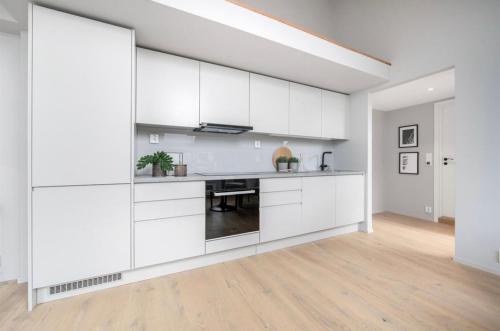 a white kitchen with white cabinets and a table at Apartment in Greenland, Oslo in Oslo