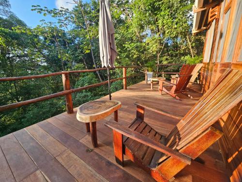 una terraza de madera con bancos y sombrilla en La Casa Del Mono en Minca