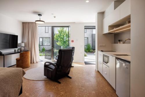 a living room with a black chair in a kitchen at Village Apartments at NZCIS in Upper Hutt