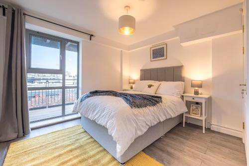 ein Schlafzimmer mit einem Bett und einem großen Fenster in der Unterkunft Victoria Brand new, cosy 1 bed apartment in London