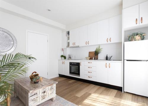 a kitchen with white cabinets and a refrigerator at Currumbin Beach 1 bedroom Studio - steps from the beach! in Gold Coast
