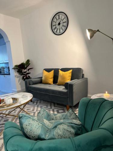 a living room with a couch and a clock on the wall at Artistic Two bedroom apartment in London
