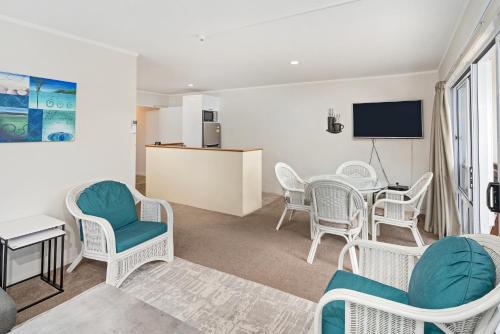 a living room with a table and chairs and a tv at Waterfront Apartments Whitianga in Whitianga