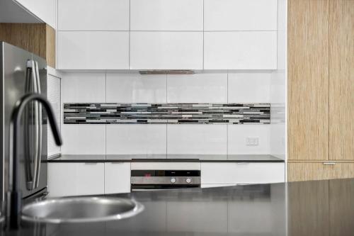 a kitchen with white cabinets and a stainless steel sink at 252 David Low Way in Peregian Beach