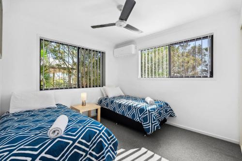 a bedroom with two beds and two windows at 252 David Low Way in Peregian Beach