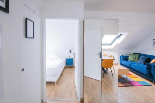 ein Wohnzimmer mit einem blauen Sofa und ein Schlafzimmer in der Unterkunft Le Champs-Elysees - Cité universitaire Paris 14 in Gentilly