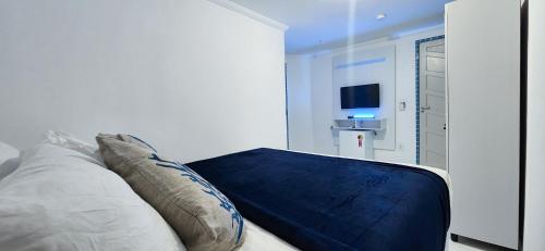 um quarto com uma cama com almofadas e uma televisão em Zenith em Arraial do Cabo