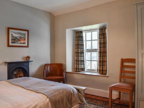 a bedroom with a bed and a window and chairs at Lingmoor View in Ambleside