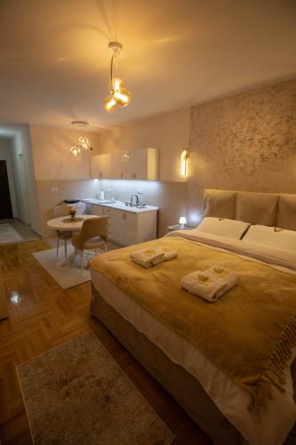 a bedroom with a large bed and a kitchen at Lotos Apartments in Kruševac