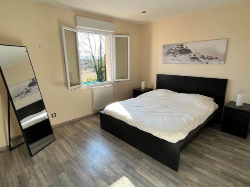 une chambre avec un lit et une grande fenêtre dans l'établissement Villa piscine proche de Genève et du Jura, à Saint-Genis-Pouilly