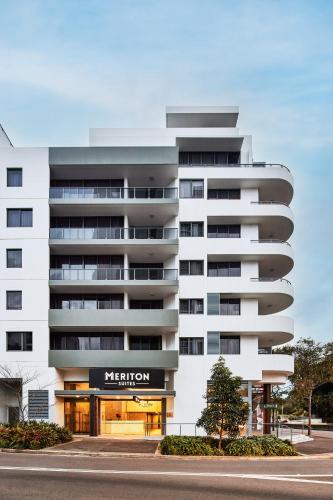 a white building with a sign for a hotel at Meriton Suites Waterloo in Sydney