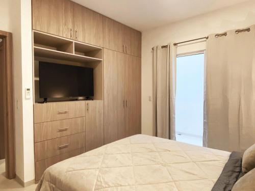 a bedroom with a flat screen tv and a bed at Suite 5, Las Castañas in Manglaralto