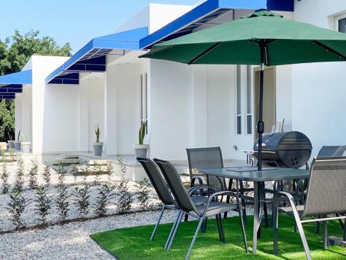 a table and chairs with a green umbrella at Suite 5, Las Castañas in Manglaralto