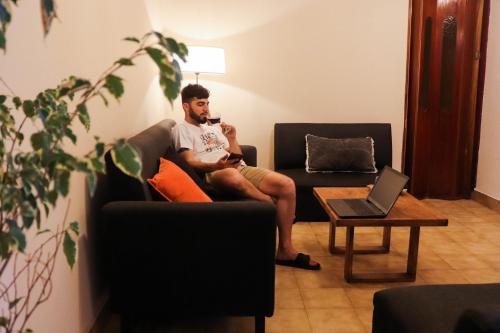 a man sitting on a couch using a cell phone at LA CASA DE LA NONA in Guaymallen