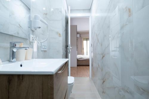 een witte badkamer met een wastafel en een douche bij Trio Apartment's City Center Tirana in Tirana