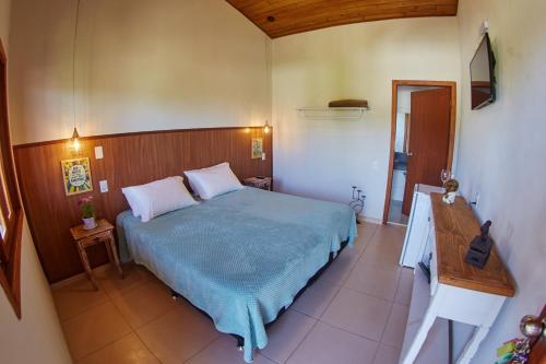 um quarto com uma cama azul e uma cabeceira em madeira em Pousada Lagoa do Rosa em Praia do Rosa