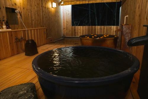 a large black tub in a room with a wooden floor at 北軽井沢　Golden Forest Hotel in Naganohara