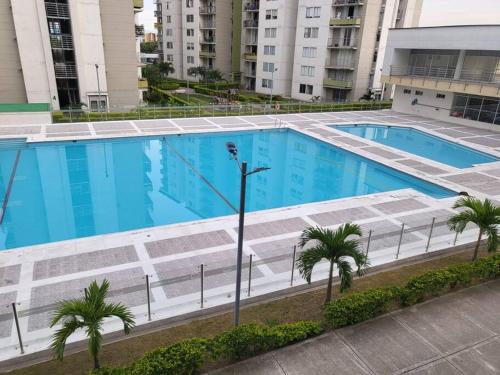 uma grande piscina com palmeiras e edifícios em ¡Hermoso y cómodo apartamento! em Ibagué