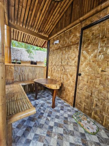 a room with a wooden table and a bench at Big BamBoo Beach Resort Sipalay in Sipalay