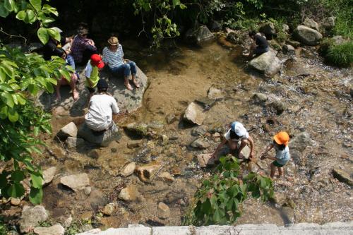 a group of people playing in a river with rocks at 88 House Hiroshima in Hiroshima