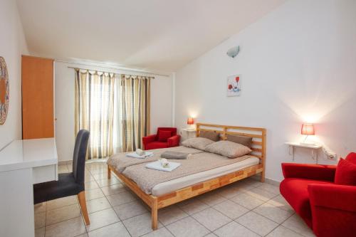 a bedroom with a bed and two red chairs at Apartments by the sea Pirovac, Sibenik - 6447 in Pirovac