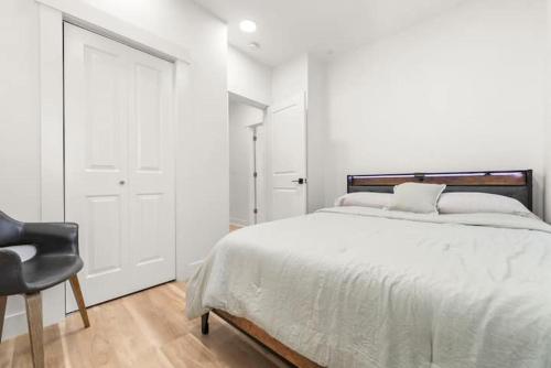 a white bedroom with a bed and a chair at 10Guests! Parking 1ST FLOOR-Duplex in Fair Lawn