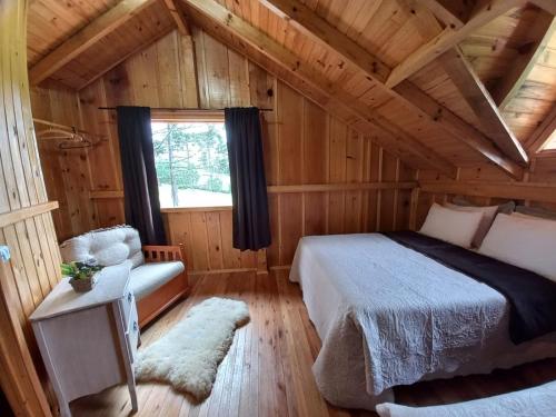 a bedroom in a log cabin with a bed and a chair at Chalés Sol da Serra in Rio Rufino