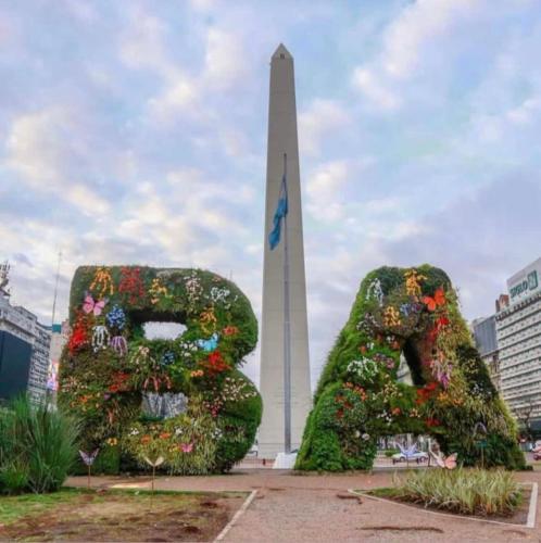 un monumento con dos grandes arbustos frente a una torre en Baires Alquileres en Buenos Aires