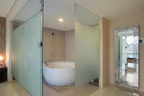 a bathroom with a tub and a glass shower door at Grand Edge Hotel Semarang - CHSE Certified in Semarang