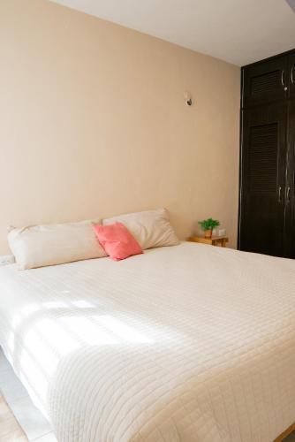 a white bed with a pink pillow on top of it at Amplia casa con 3 habitaciones para hospedaje in Chetumal
