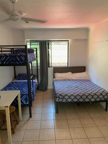 a room with two bunk beds and a table at Arrival Lodge Hostel Accommodation in Gold Coast