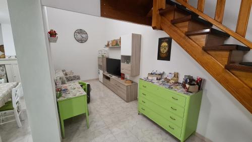 a living room with a green dresser and a staircase at Casa vacanze Galena in Iglesias