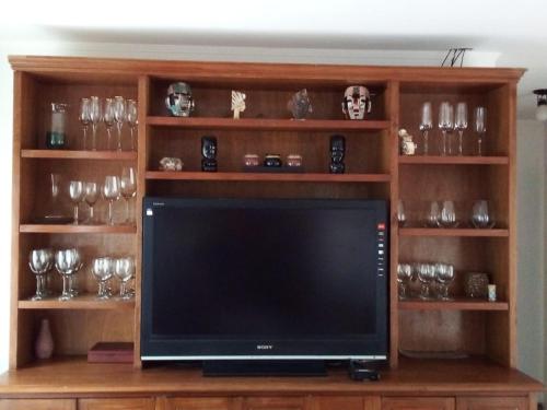 a tv sitting on a wooden shelf with glasses at Casa en Cariló para 16 personas in Carilo
