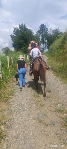 a woman walking down a dirt road with a horse at Finca Maratón Alto in Calarcá
