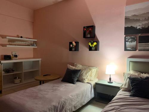 a bedroom with two beds and a table with a lamp at KRCB Suite Evo Mall Bangi in Bangi