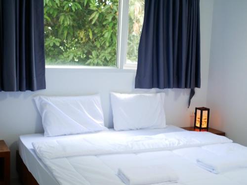a bed with white sheets and pillows in front of a window at ศิวพฤกษ์ เพลส in Nonthaburi