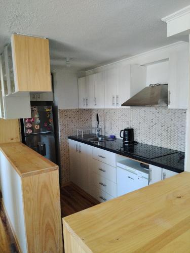 une cuisine avec des placards blancs et un comptoir noir dans l'établissement Departamento Amoblado, à Quilpué