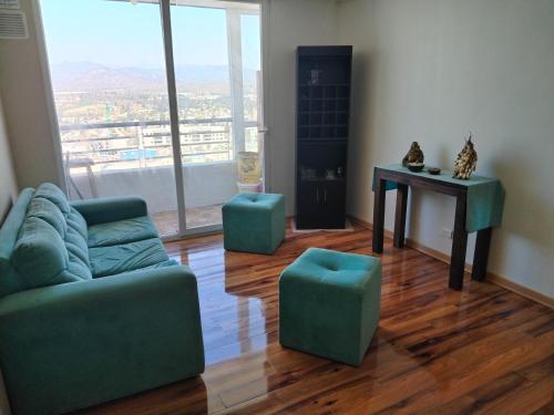 Sala de estar con sofá, 2 taburetes y mesa en Departamento Amoblado, en Quilpué