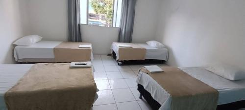 a room with three beds and a window at Pousada Praia Avenida in Maceió