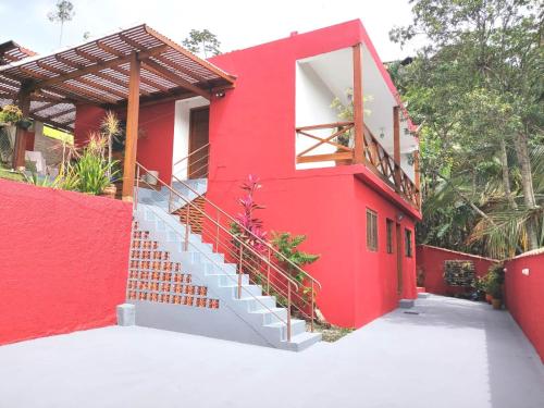 una casa roja con una escalera delante de ella en Apartamento em Ilha bela, en Ilhabela