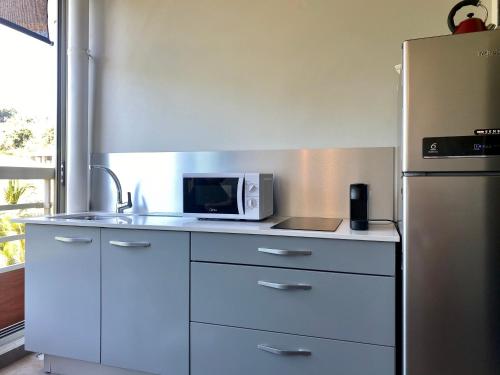 a kitchen with a microwave and a refrigerator at Iaorana Tahiti in Arue