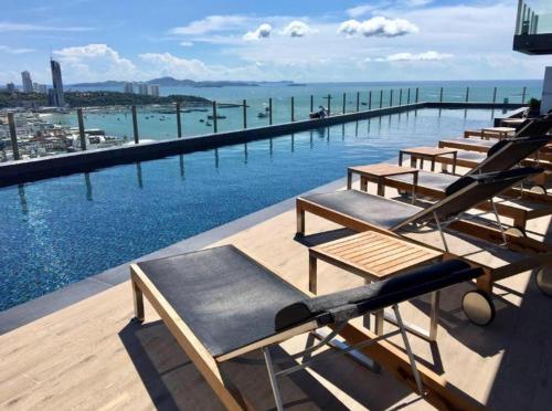 a row of chaise lounges on the edge of a swimming pool at BASE Central PATTAYA Quiet King-Bed with Infinity Pool in Pattaya