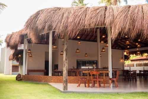 un restaurante con mesa y sillas bajo un techo de paja en POUSADA E RESTAURANTE GAROUPA, en São Miguel dos Milagres